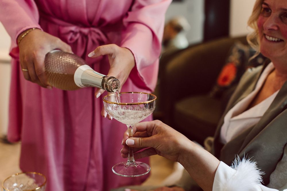 Friends in pink robes holding champagne glasses during celebration gathering.