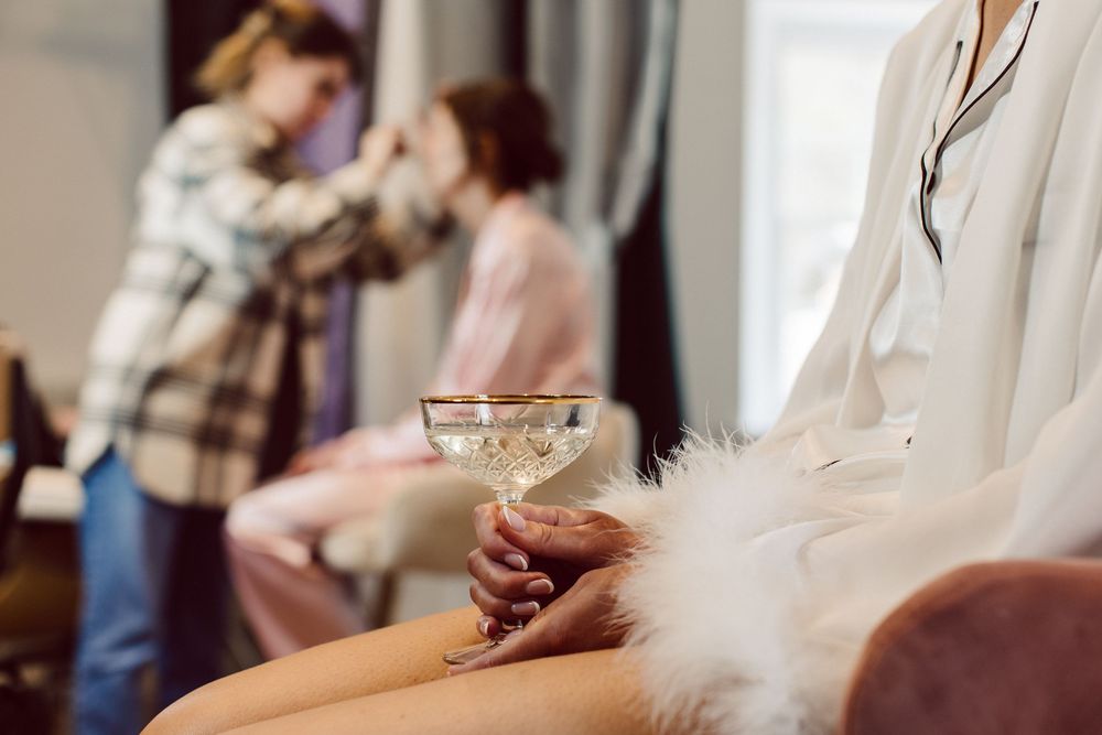 Person holding a martini glass while sitting on couch during a social gathering in a living room setting.