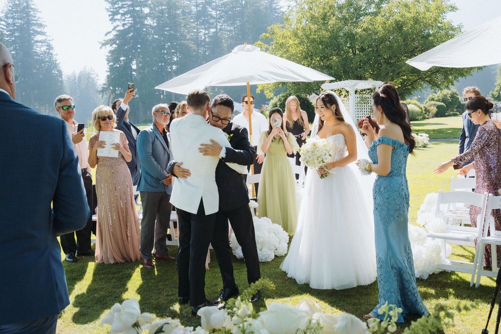 Newlyweds walk back down aisle as guests celebrate at outdoor summer wedding ceremony.