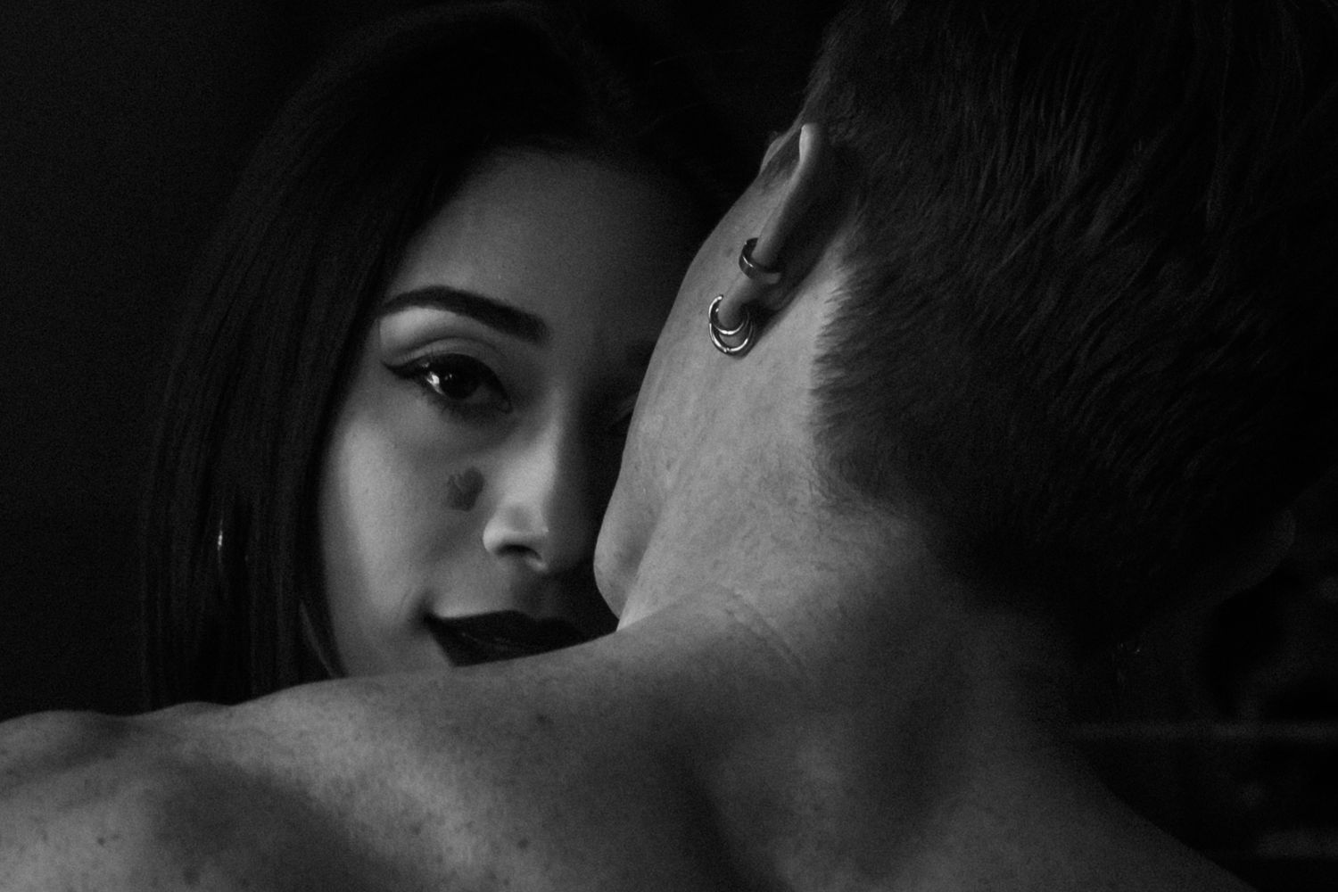 Black and white close-up of a woman and man in an intimate moment, woman wearing hoop earring.