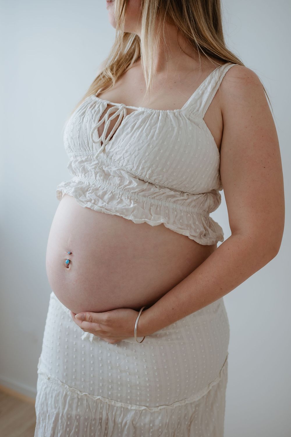 A series of photos showing a pregnant belly in a white textured dress against a light background.