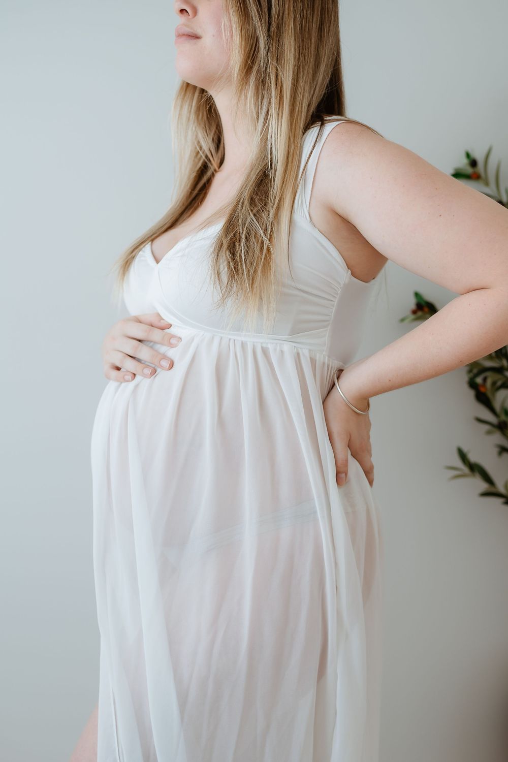 A person wearing a flowing white sleeveless dress stands against a light background showing different angles of the garment.