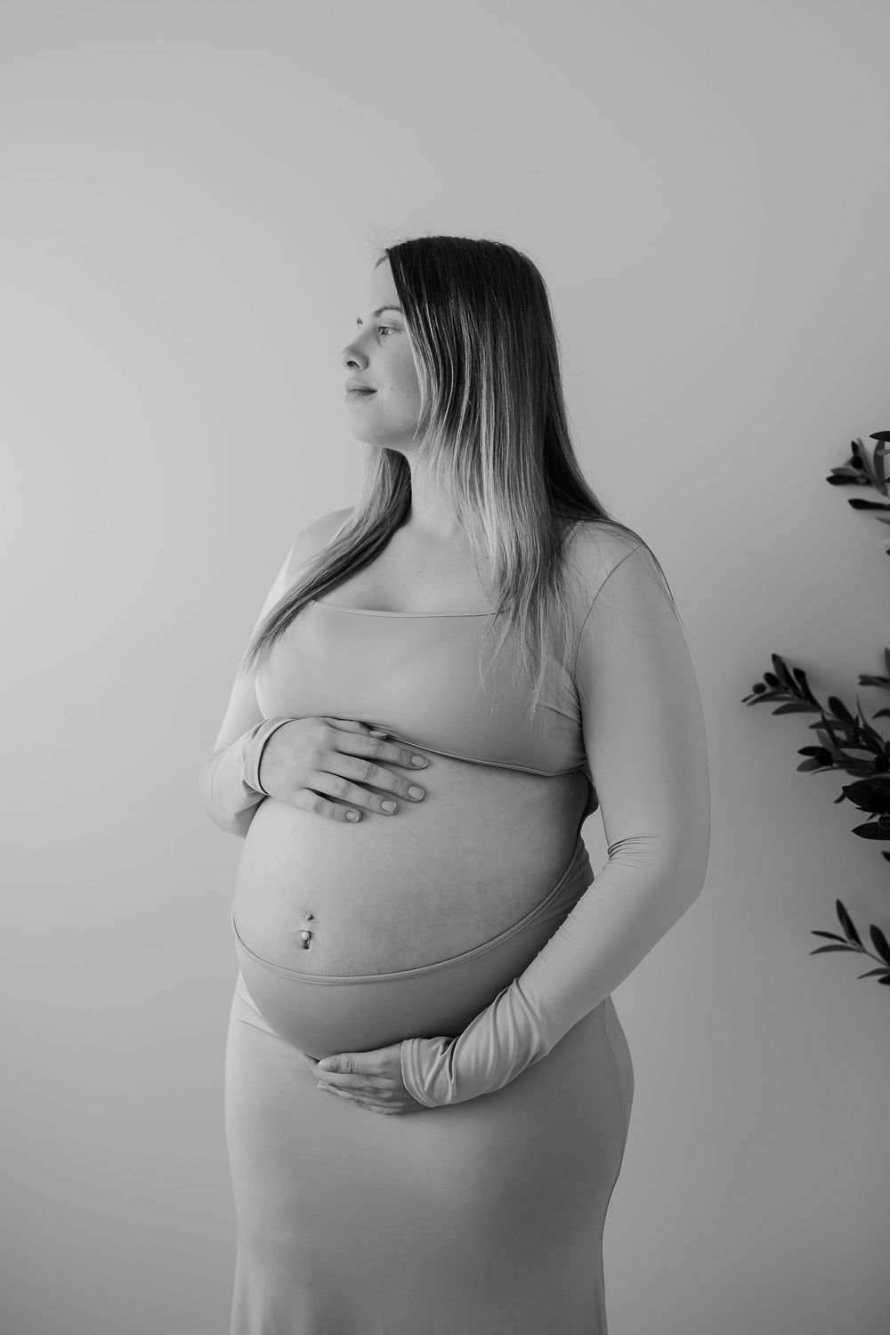 Black and white maternity photo series showing pregnant belly in various angles against a minimalist background.