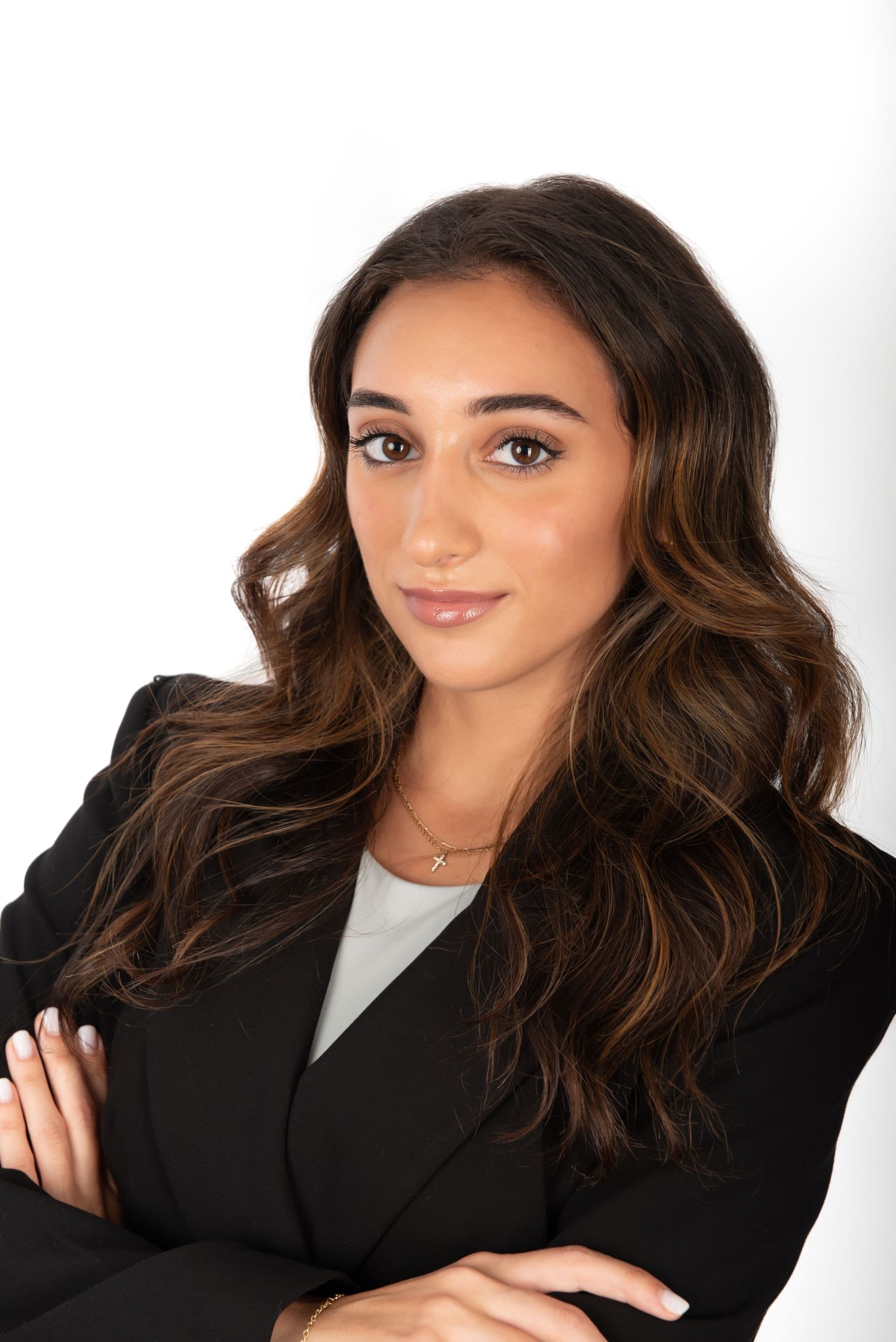 A young women poses on a white backdrop for a headshot.