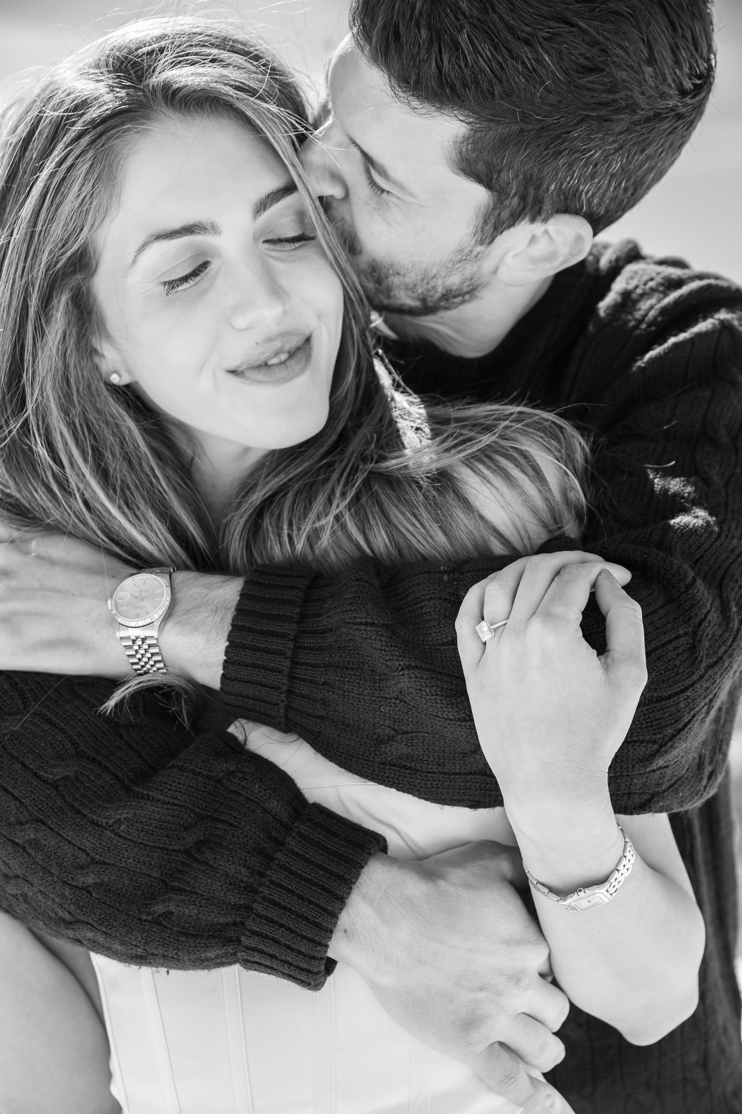 Black and white photo of a bearded man embracing and kissing a smiling woman for engagement photos in Vail Colorado.