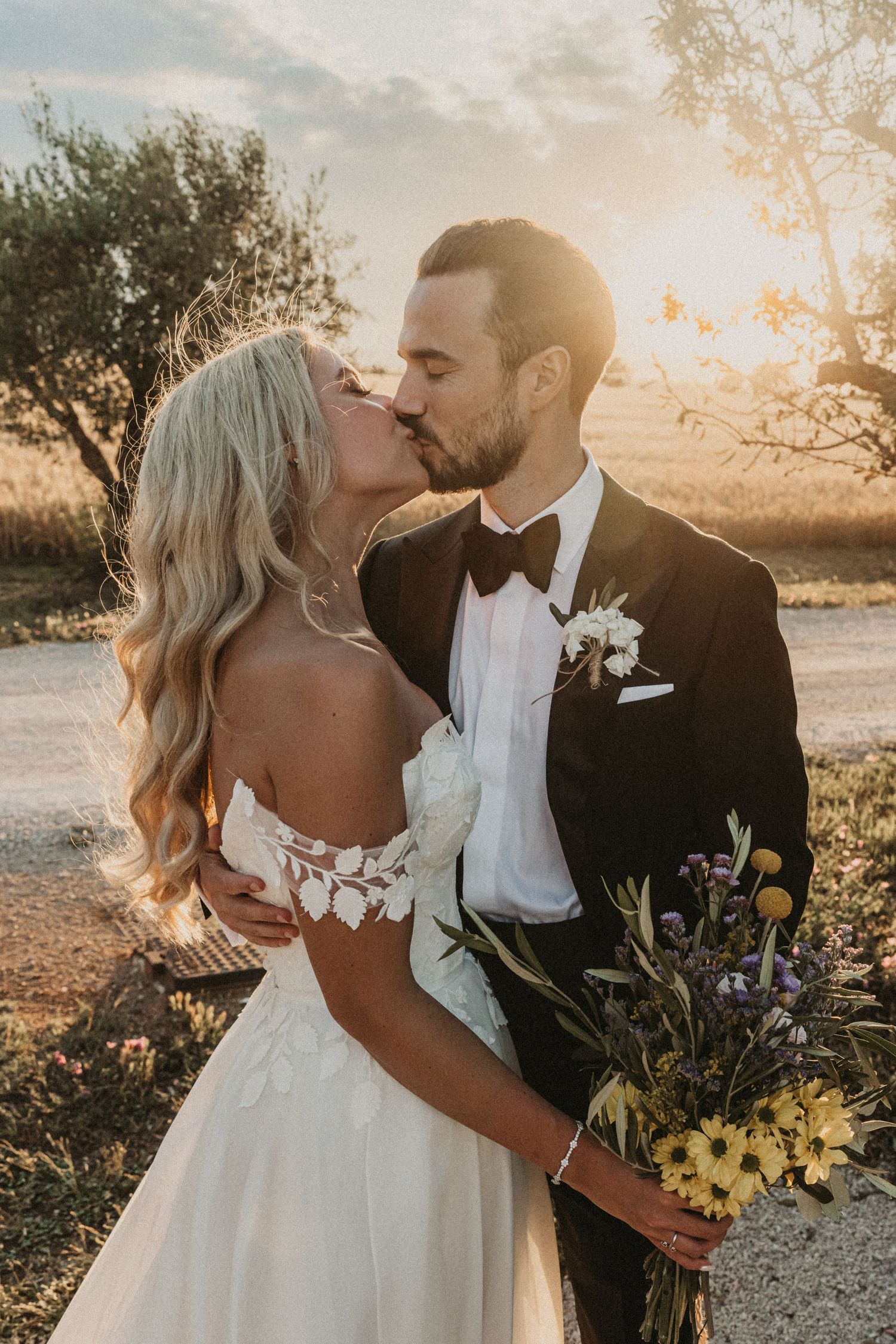 Romantic sunset wedding portraits show a couple sharing intimate kisses in a rustic outdoor setting with golden light.