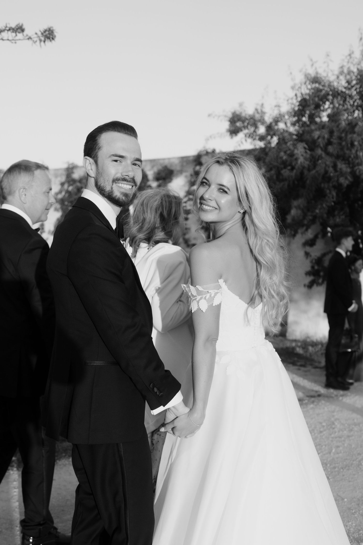 A series of black and white wedding photos showing joyful moments between a couple in formal attire outdoors.