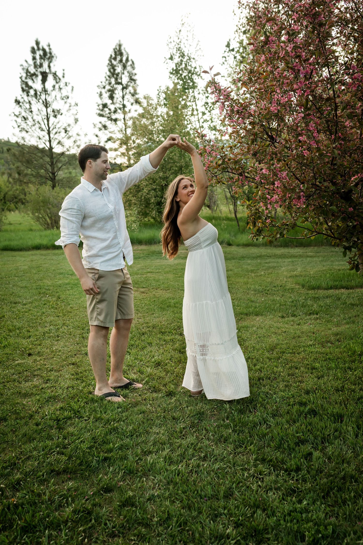 Romantic couple by cherry blossom trees during springtime in Calgary. Love & Sunshine Photography.