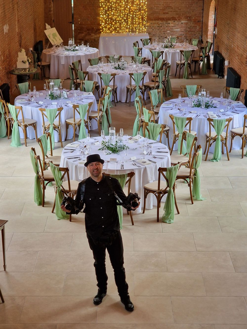 Elegant wedding reception venue with round tables decorated in white linens and mint green chair sashes.