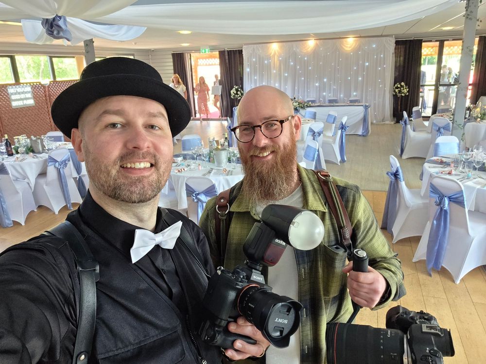 Wedding photographers with cameras working together in a decorated reception hall.