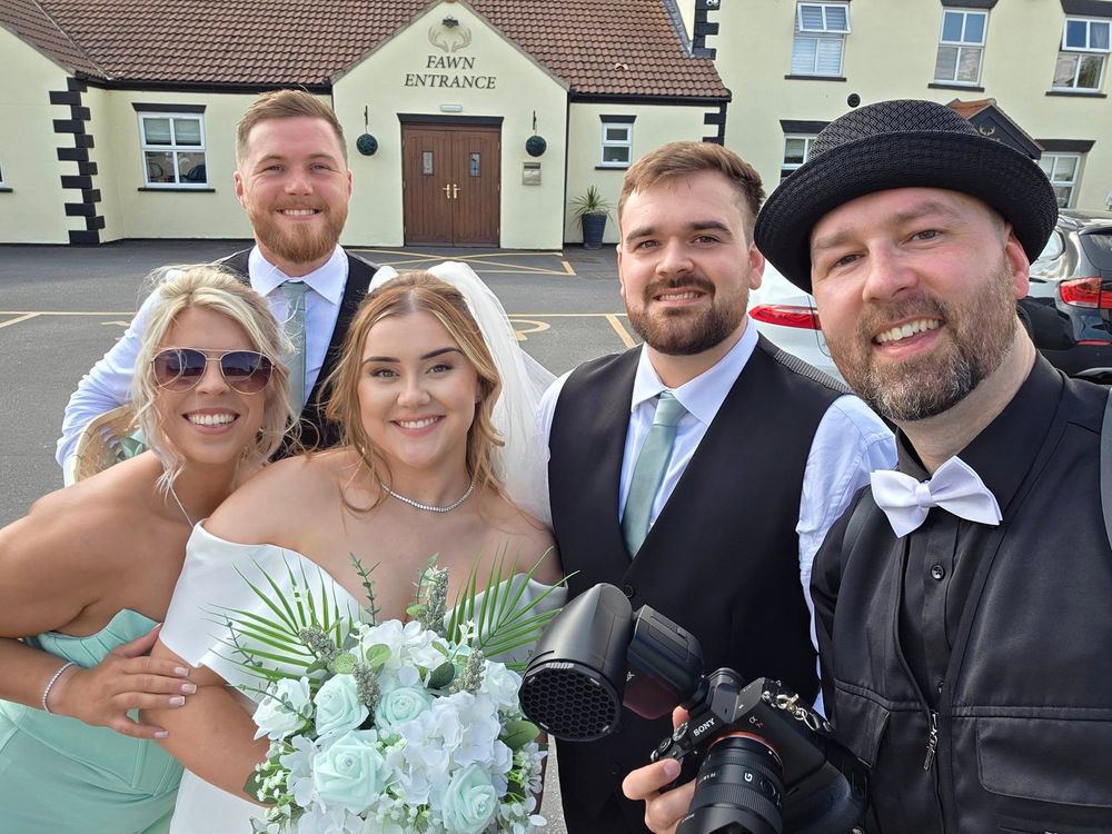 Wedding party gathered outside a traditional British pub with mint green and white color scheme.