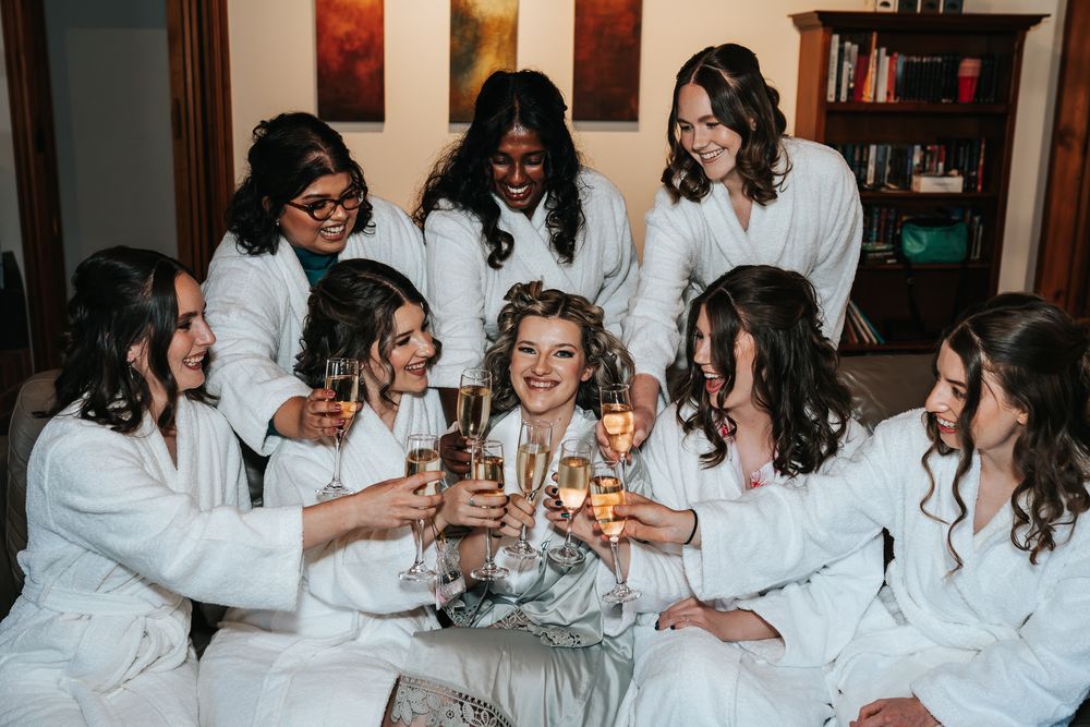 Bride and bridesmaids in their getting ready gowns with glasses on champagne having a toast taken by a Melbourne wedding photographer.