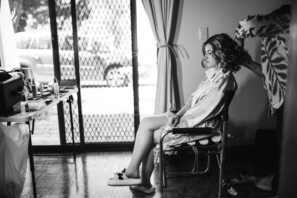 Black and white photo of a bride having her hair done by the hairstylist taken by a Melbourne wedding photographer.