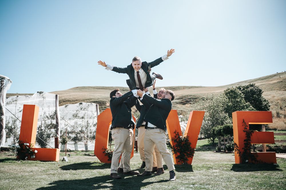 Groom got tossed in the air by his groomesmen with a huge LOVE signage at the wedding venue taken by the a Melbourne wedding photographer.