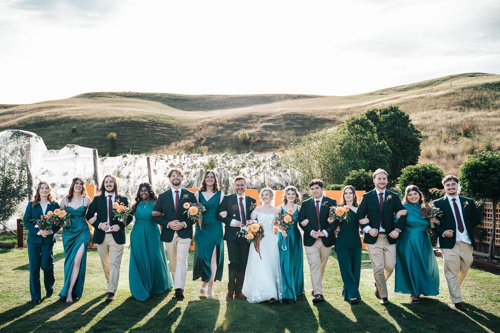 The whole wedding party walking with arms linked on a straight line laughing taken by Melbourne wedding photographer.