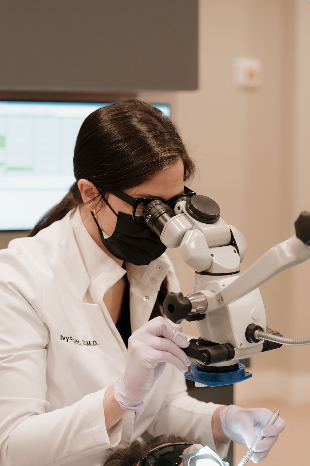Medical professional in protective gear examining samples through a microscope in a laboratory.
