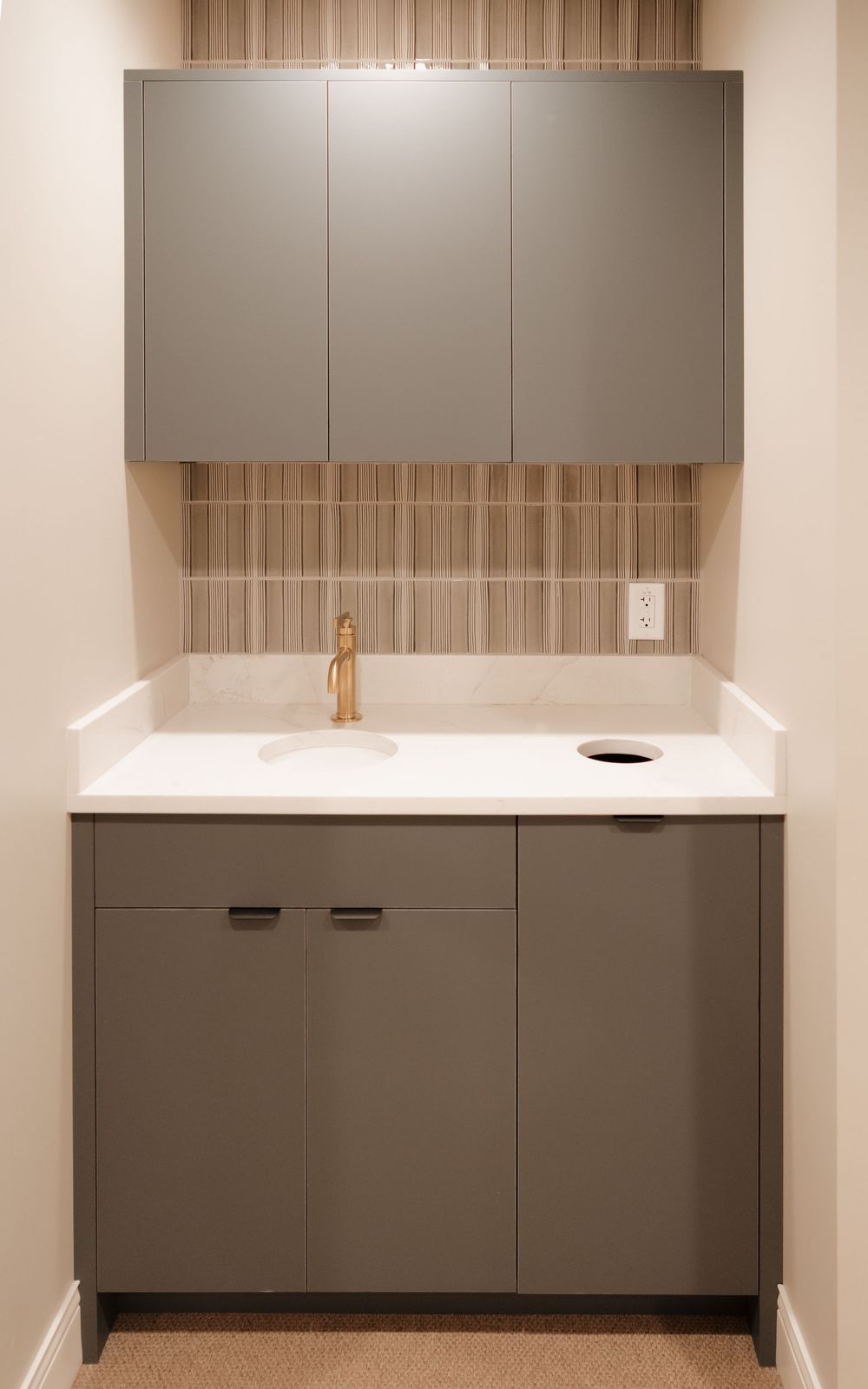 Modern gray kitchen cabinets with white countertop and brass fixtures in minimalist design.