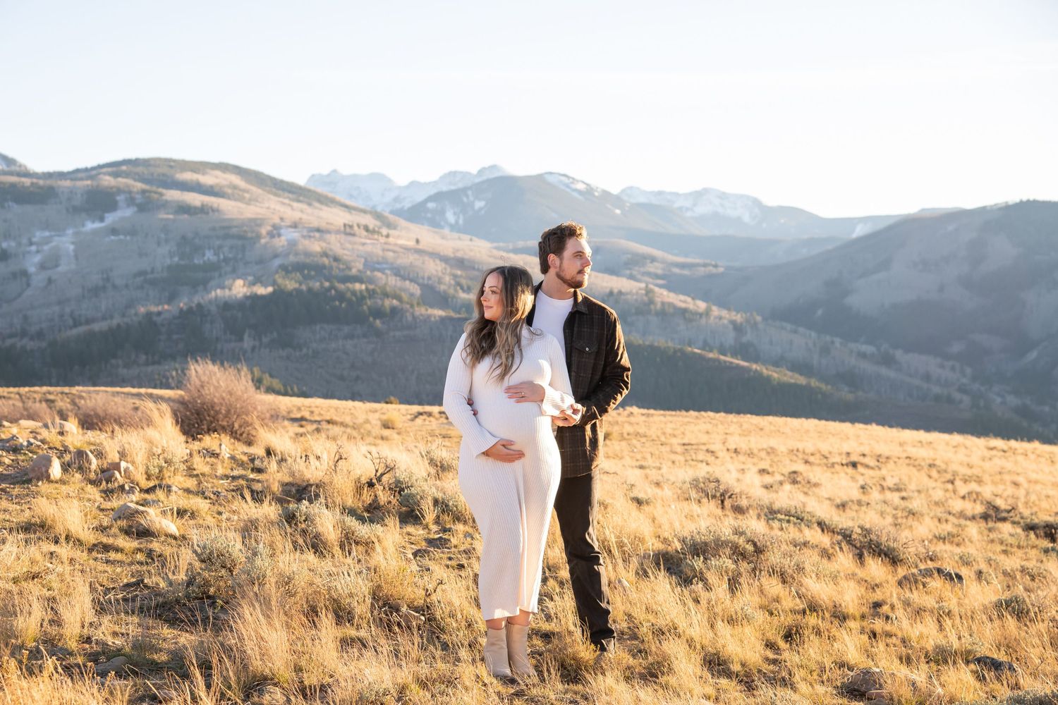 Editorial style image of a man and woman standing on top of a mountain during a Vail Colorado golden hour photo session.