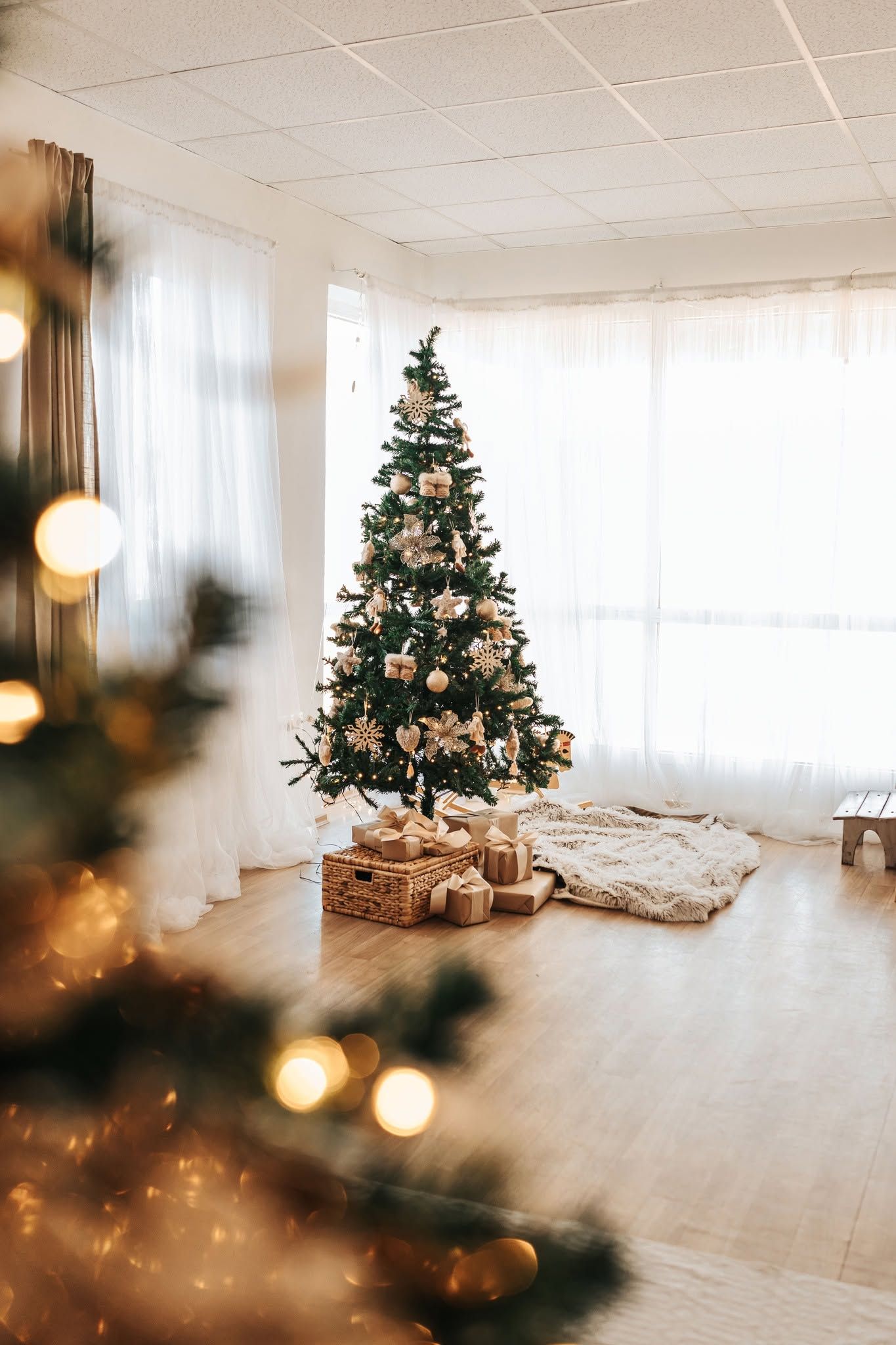 A wooden rocking horse sits in a cozy room decorated for Christmas with a tree and wall decor in warm lighting.