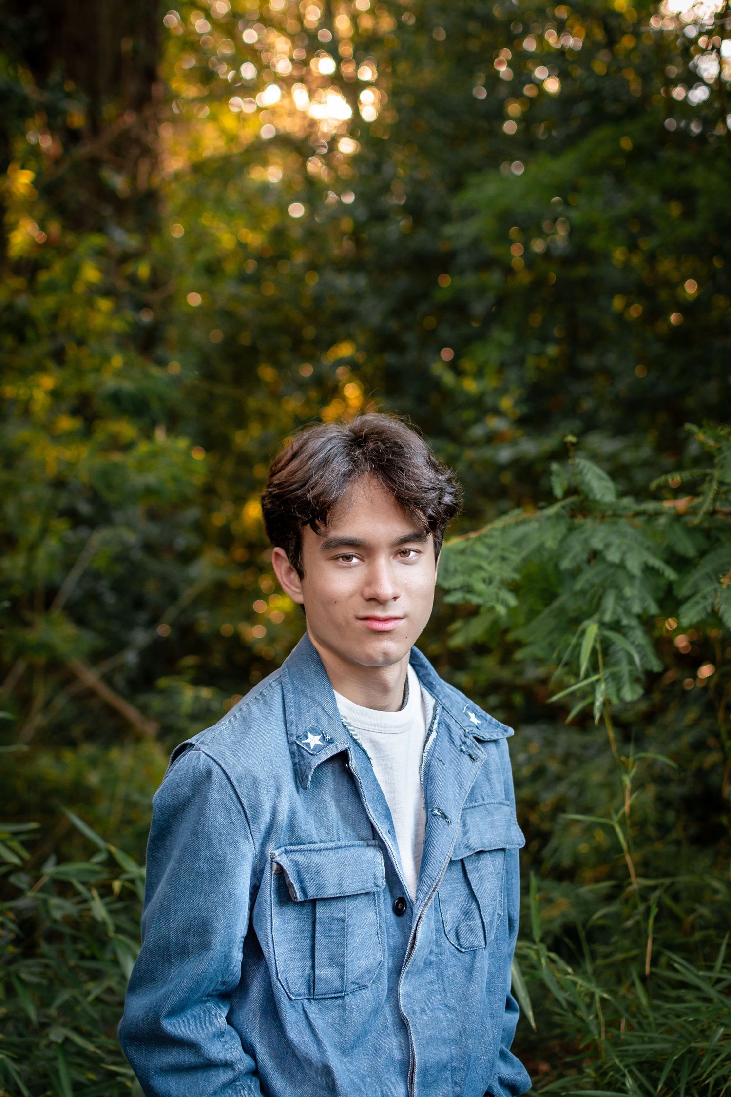 Senior portrait with golden sunlight filtering through trees at Kubota Garden