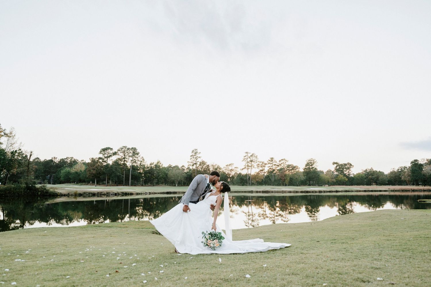 Panoramic view of an outdoor wedding ceremony setup in a serene field with white decor.