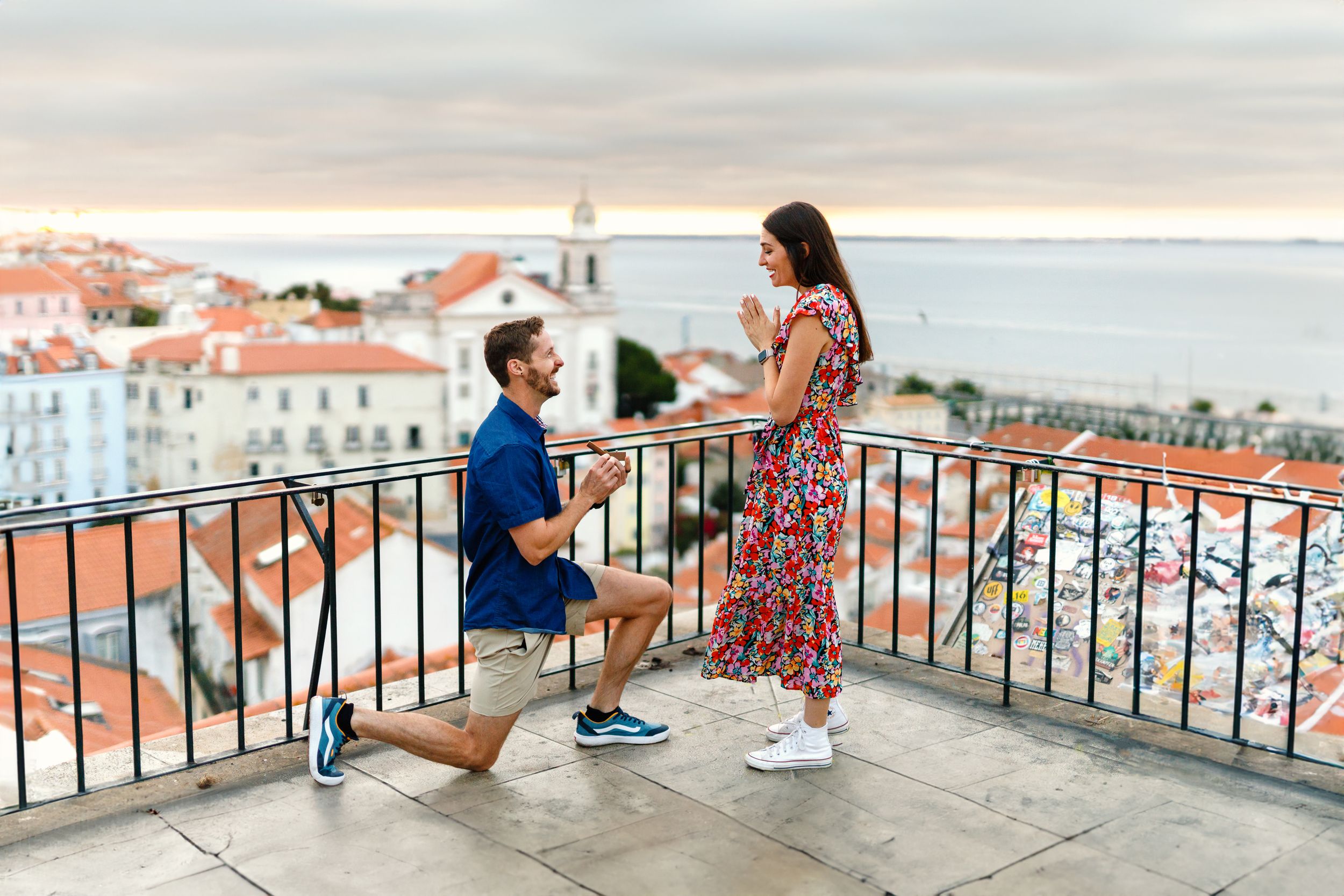 People enjoying panoramic views of a coastal city with white buildings and terracotta roofs from a scenic viewpoint.