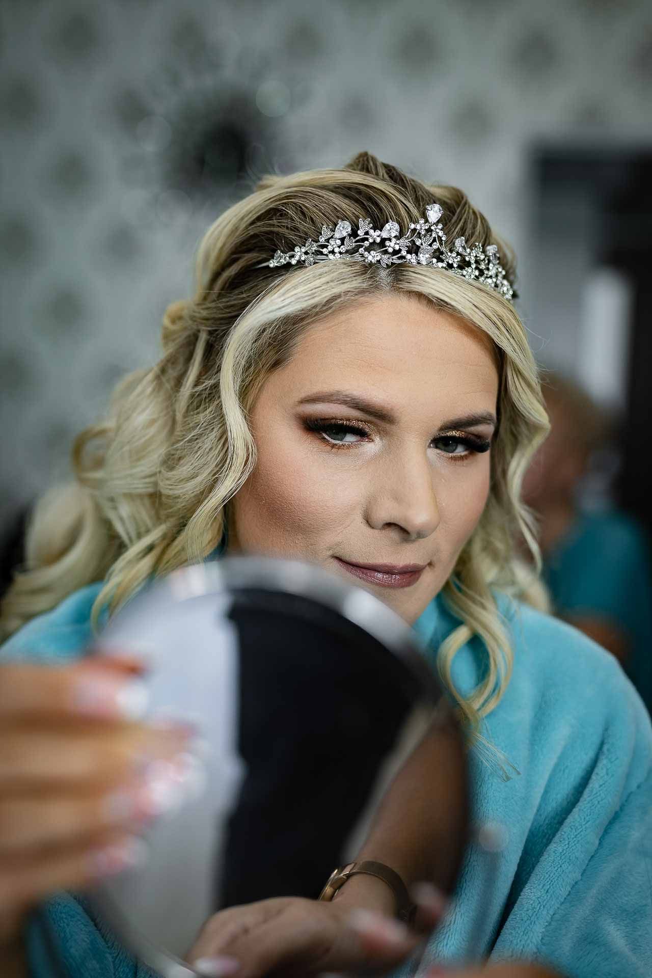 Close-up of bridal preparation with sparkly headpiece and turquoise robe.