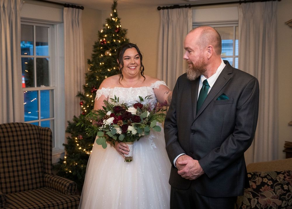 Wedding celebration in an elegant room with Christmas trees and window light creating a festive atmosphere.