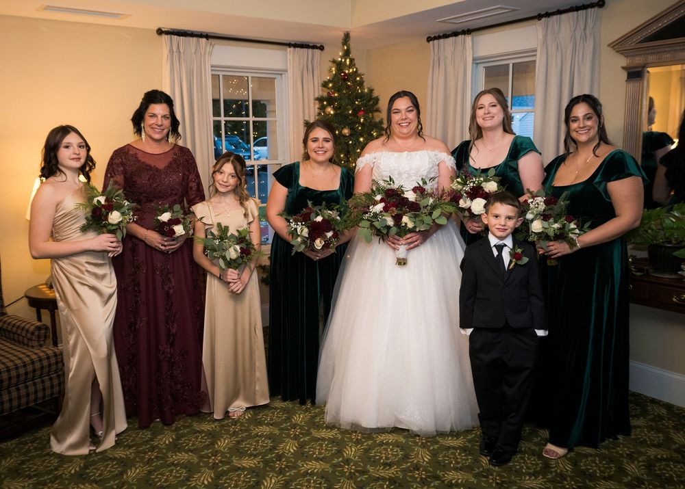 Wedding party posed together in burgundy and neutral colored dresses for formal group photo.