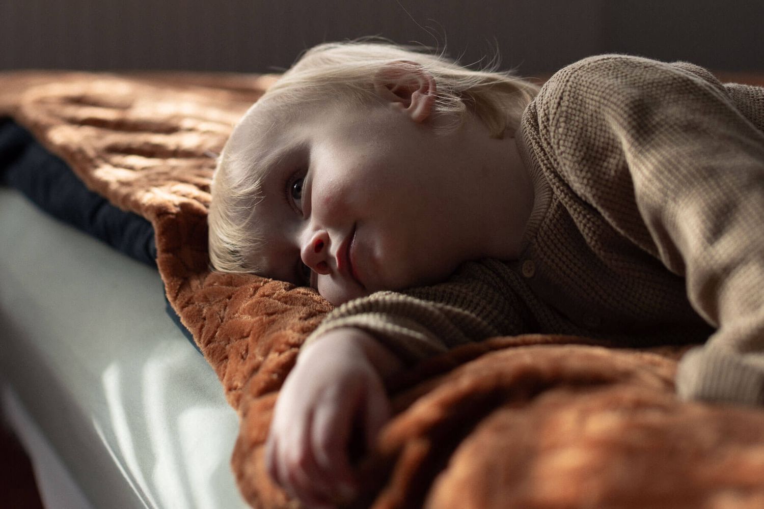 Child lying on a bed, lit by beautiful natural light, photographed during a family photography session in Brighton