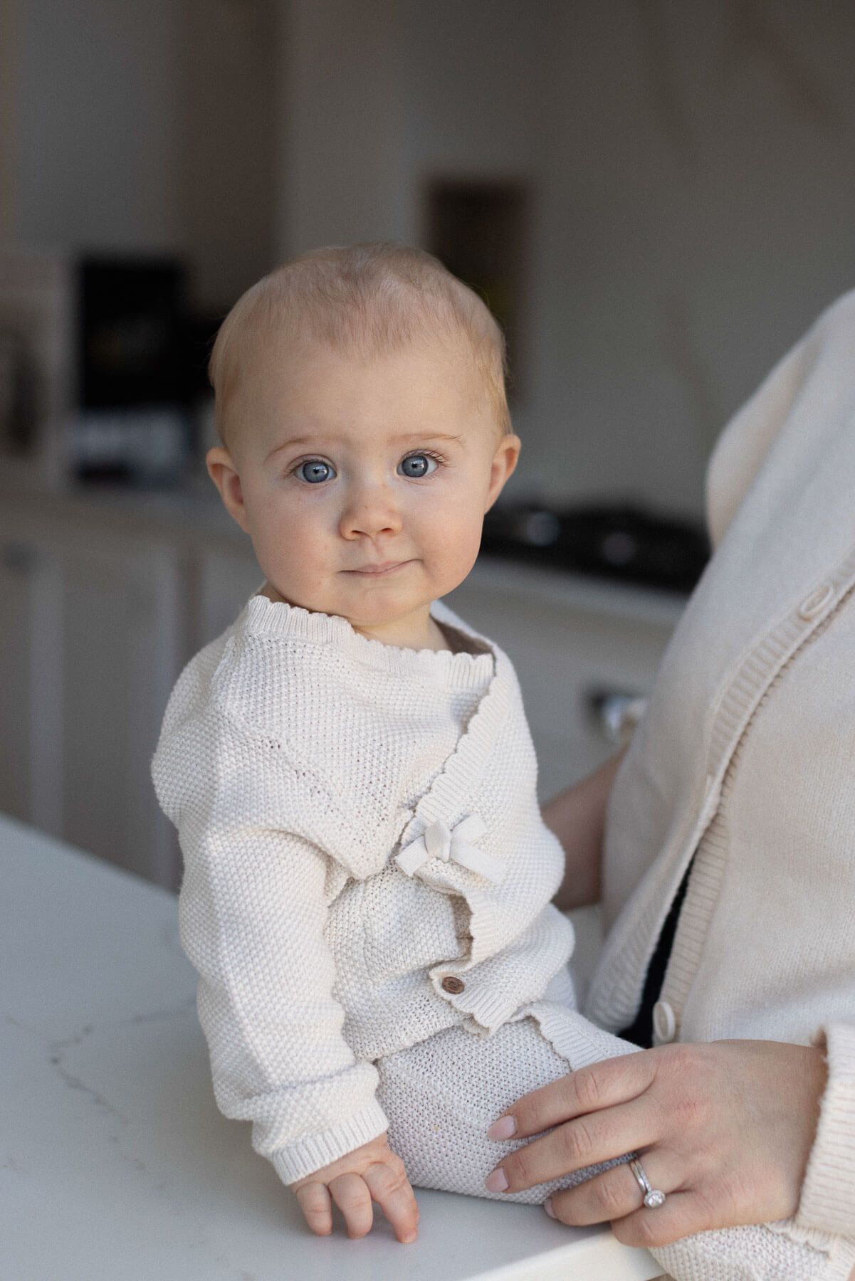 Elegant portrait of baby in soft neutral tones looking at the camera, photographed at an in home session in Brighton