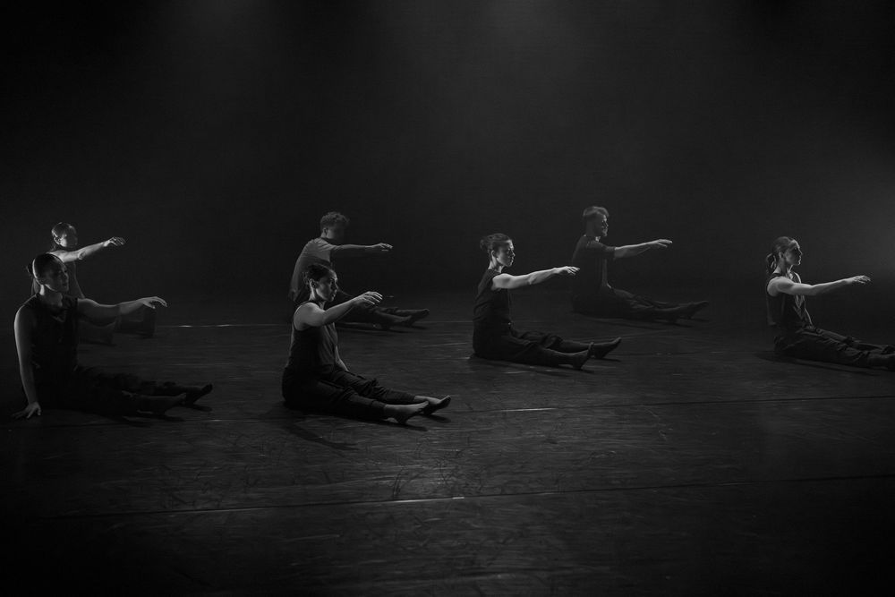 A sequence of dancers performing graceful movements in a dark studio setting.