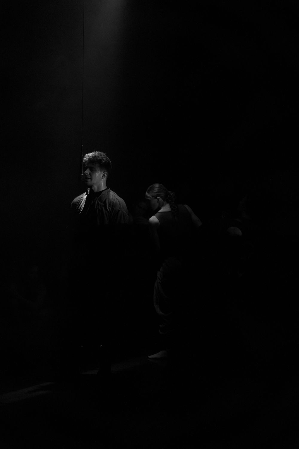 Silhouettes of performers moving in darkness with minimal lighting creating a mysterious atmosphere.