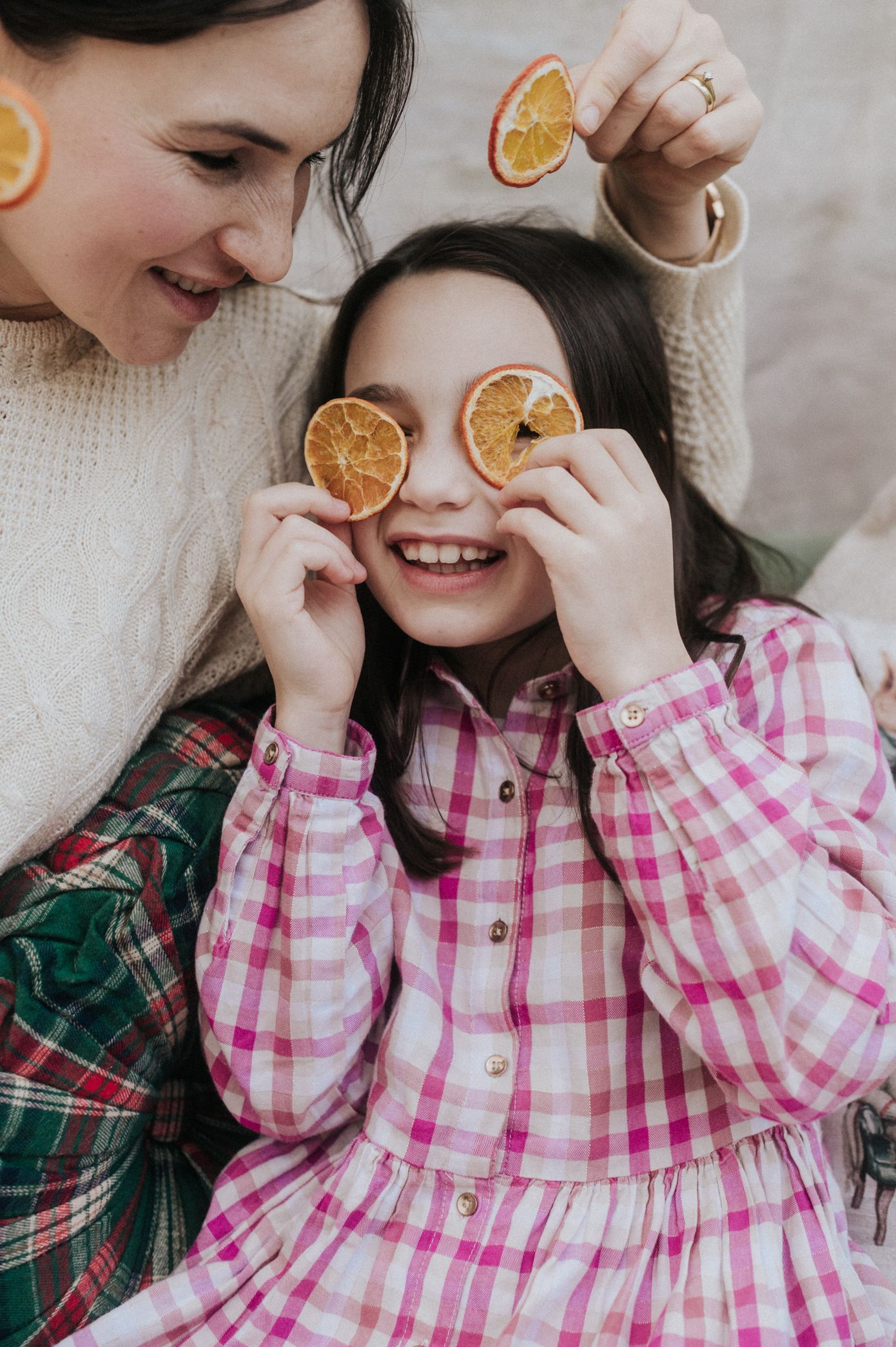 A playful series of photos showing dried orange slices being held up to eyes while wearing pink and green plaid.