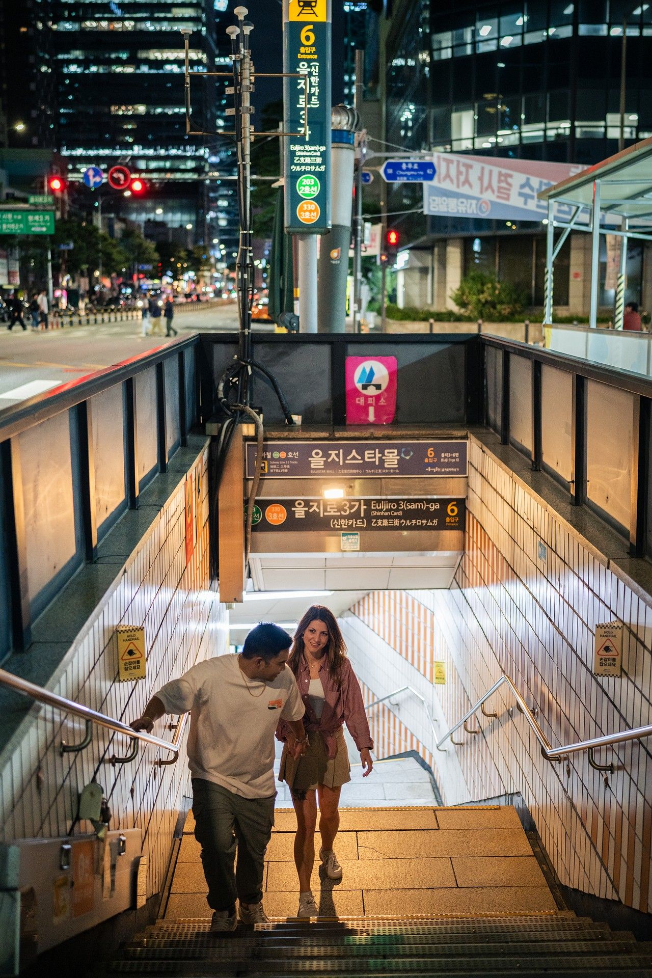People descending illuminated subway station stairs in Seoul, shown in a progressive sequence of steps.