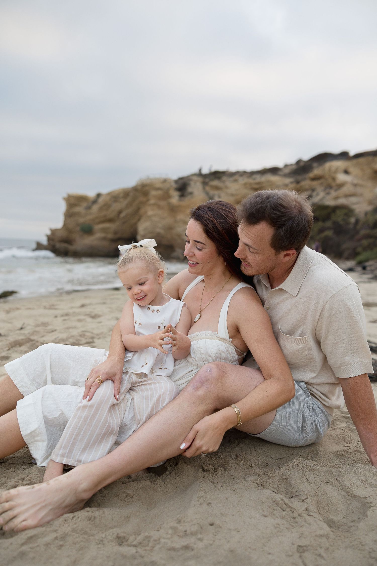 Beach family photos at Crystal Cove with parents and toddler playing in the sand