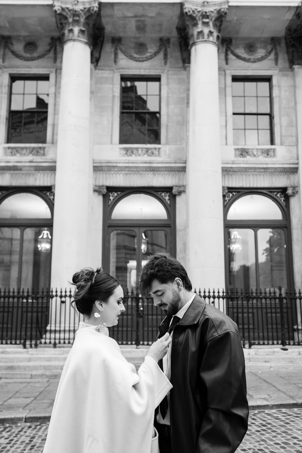 Refined editorial moment — elegant anniversary couple adjusting tie in Dublin City Hall.