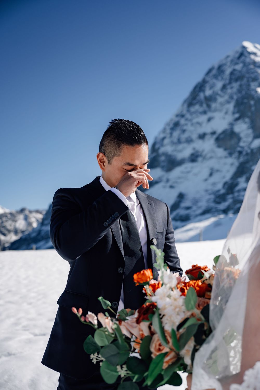 A couple shares an intimate moment during their winter mountain wedding ceremony against snowy alpine peaks.