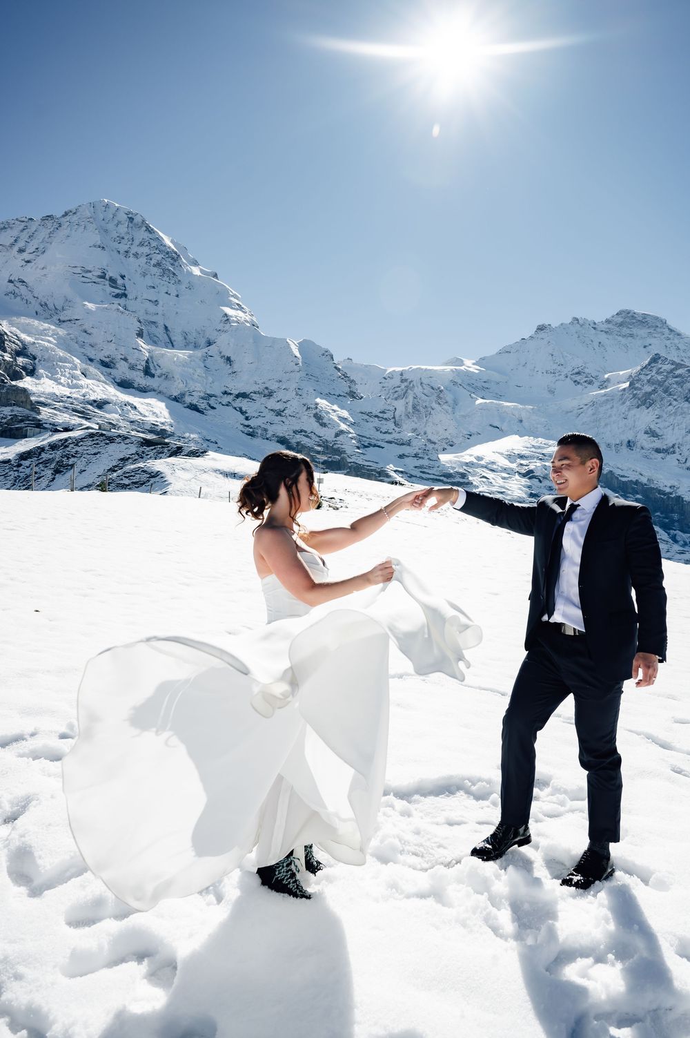 A winter wedding photo sequence showing a couple playfully posing in deep snow with snow-capped mountains in the background.