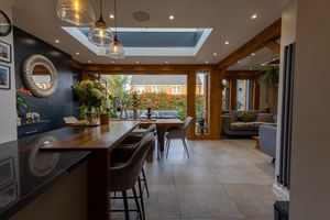 Modern open concept kitchen and dining area with skylights, pendant lighting, and panoramic windows overlooking nature.