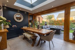 Modern dining room with navy accent wall, wooden table, bench seating and glass doors leading to outdoor patio.