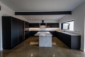 Modern open concept living space with black cabinets, concrete floors and white pendant lighting in minimalist design.
