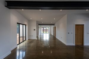 Modern office hallway with recessed lighting, wooden doors, and polished floors stretches into the distance.