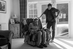 A sequence of black and white photos showing someone getting up from a recliner chair in progressive motion.