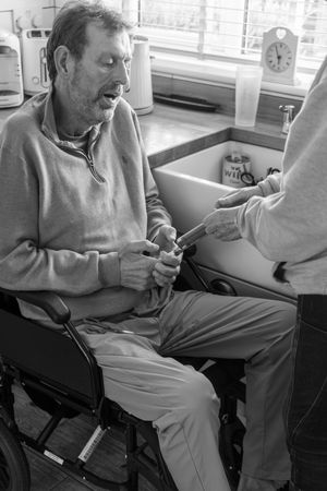 A series of black and white photos showing someone sitting in a wheelchair reading a newspaper or document.