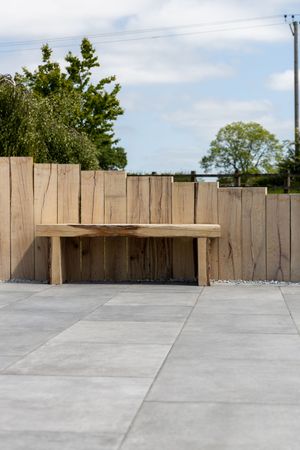 Wooden fence panels and concrete flooring create a minimalist outdoor space with trees visible in the background.