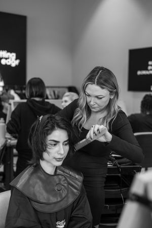 Black and white image of a hair styling session in a salon showing client getting hair done.