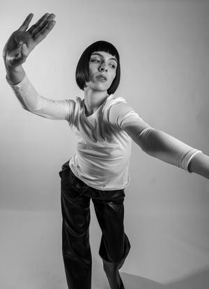 A black and white photo series showing a person in white top and dark pants performing expressive dance movements.