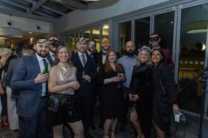Business professionals mingle and network at a modern office gathering space during an evening event.