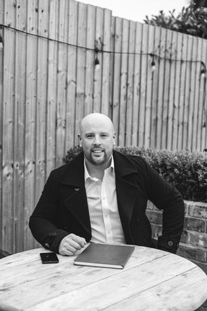 Series of black and white photos showing someone in a black jacket sitting at an outdoor table.